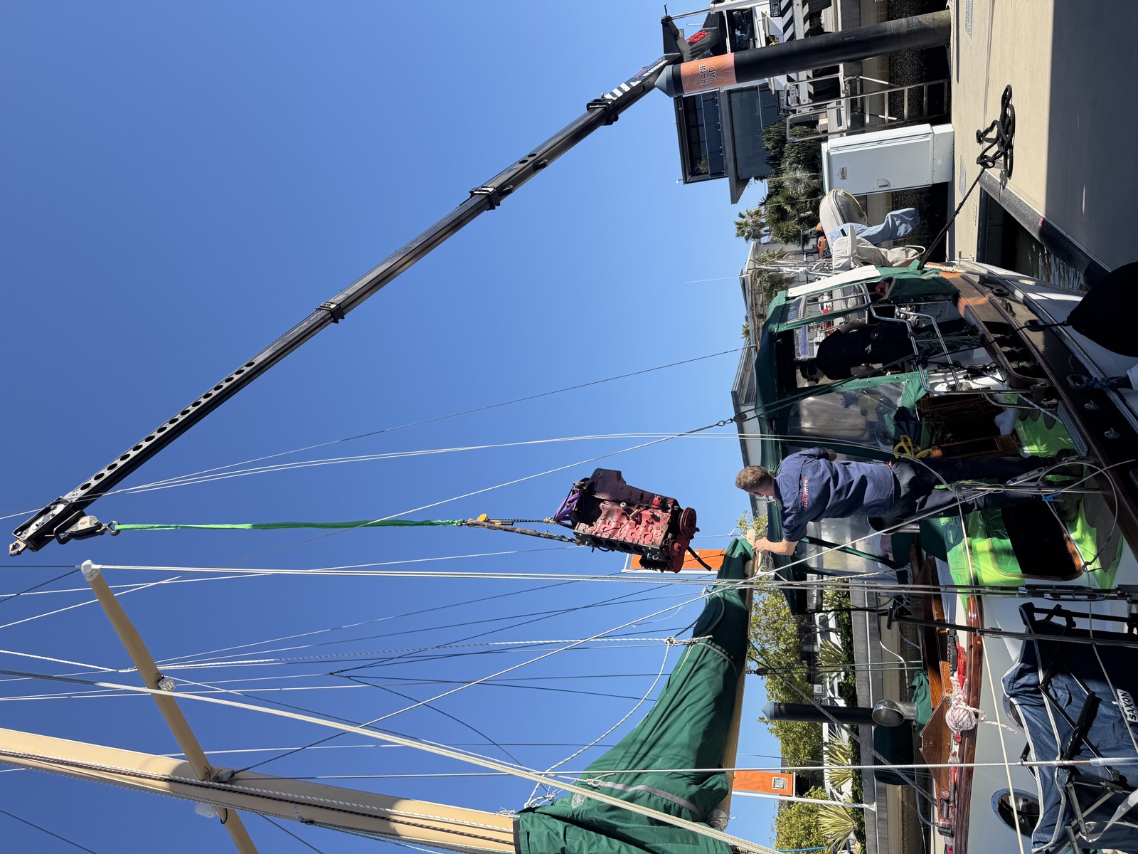 Marine engine being craned onto a timber sailing vessel at the marina