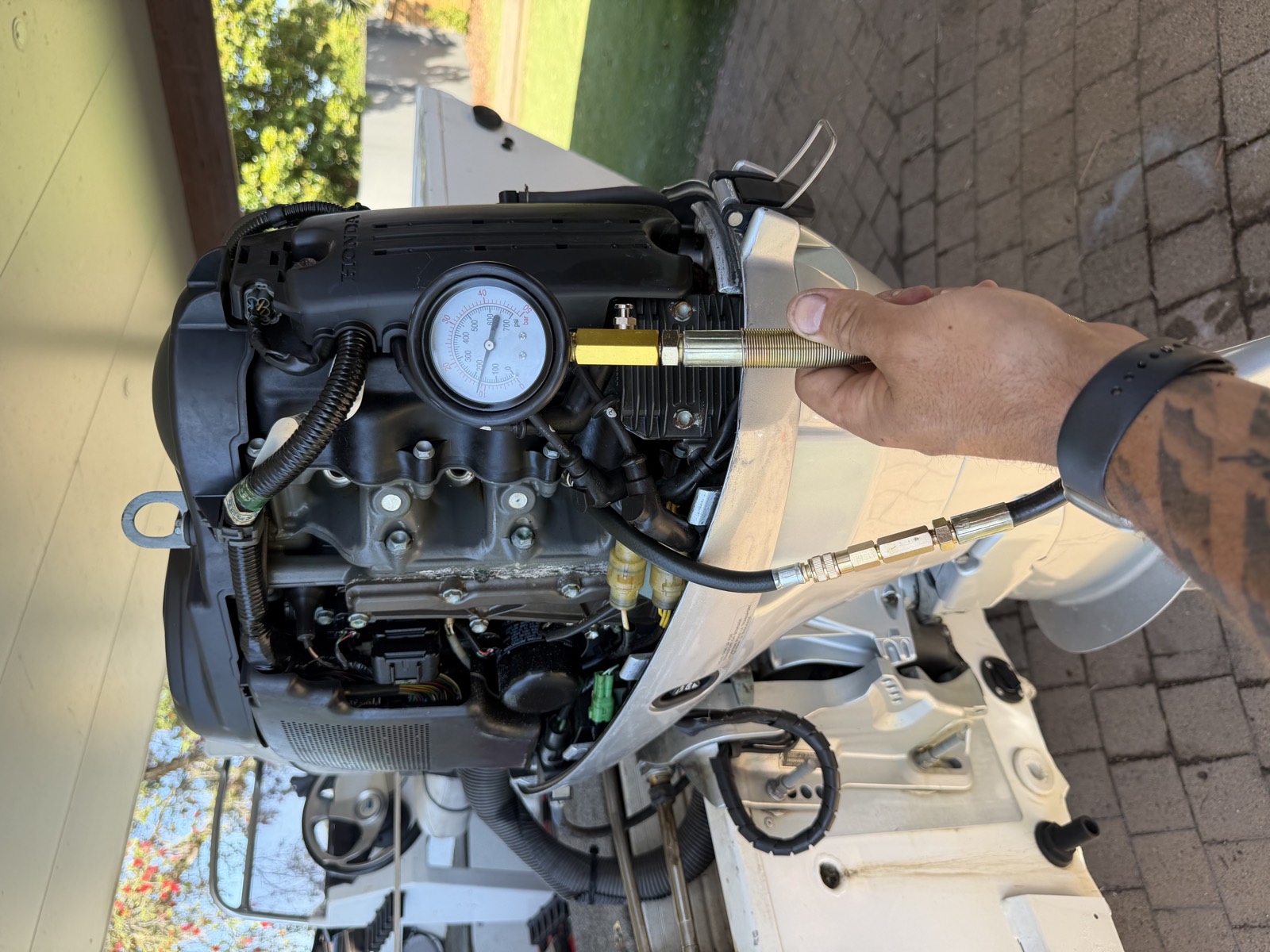 Honda outboard with the cowling removed and a compression tester fitted