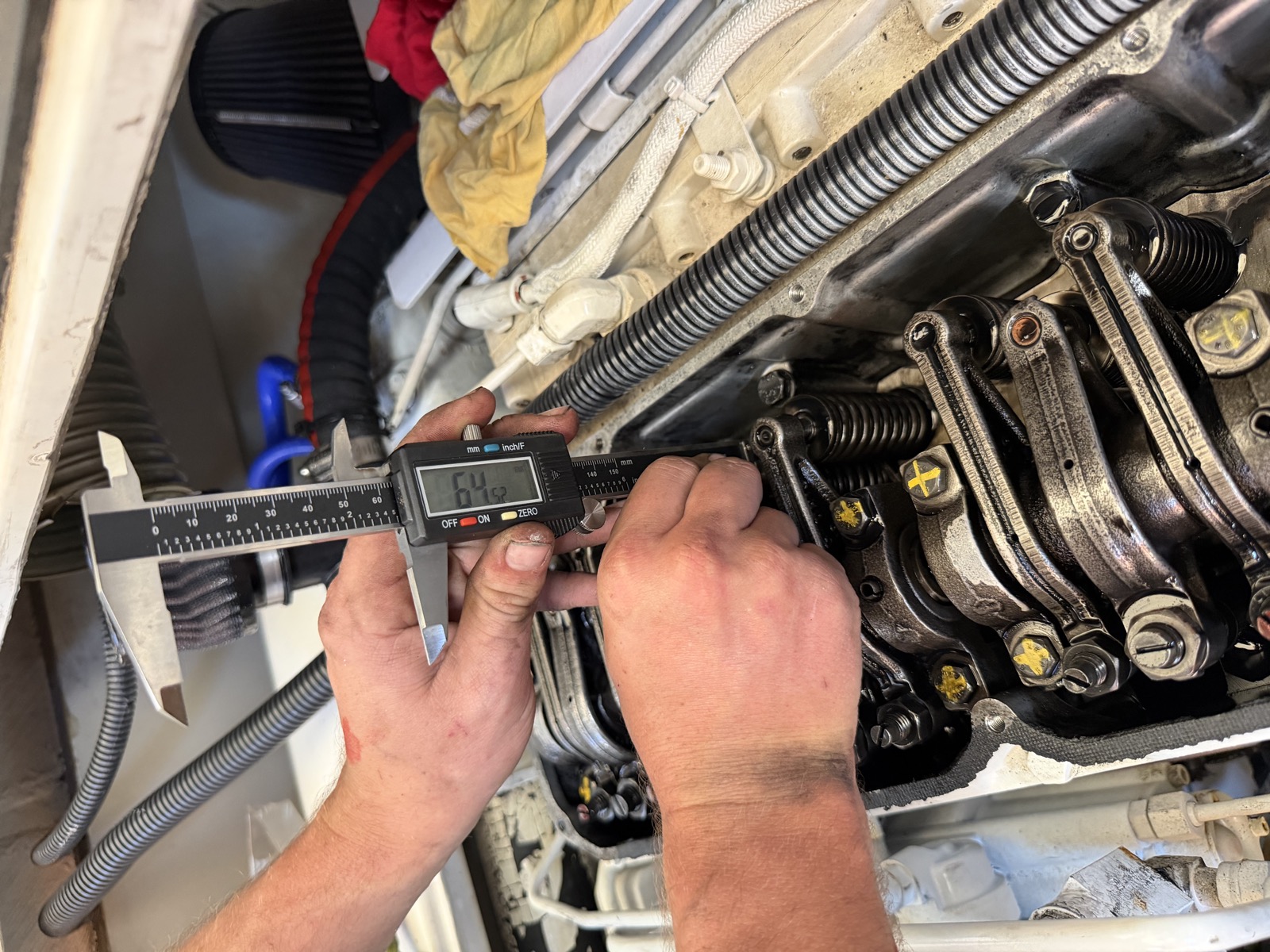 Digital calipers measuring injector height on an open Caterpillar 3126 overhead