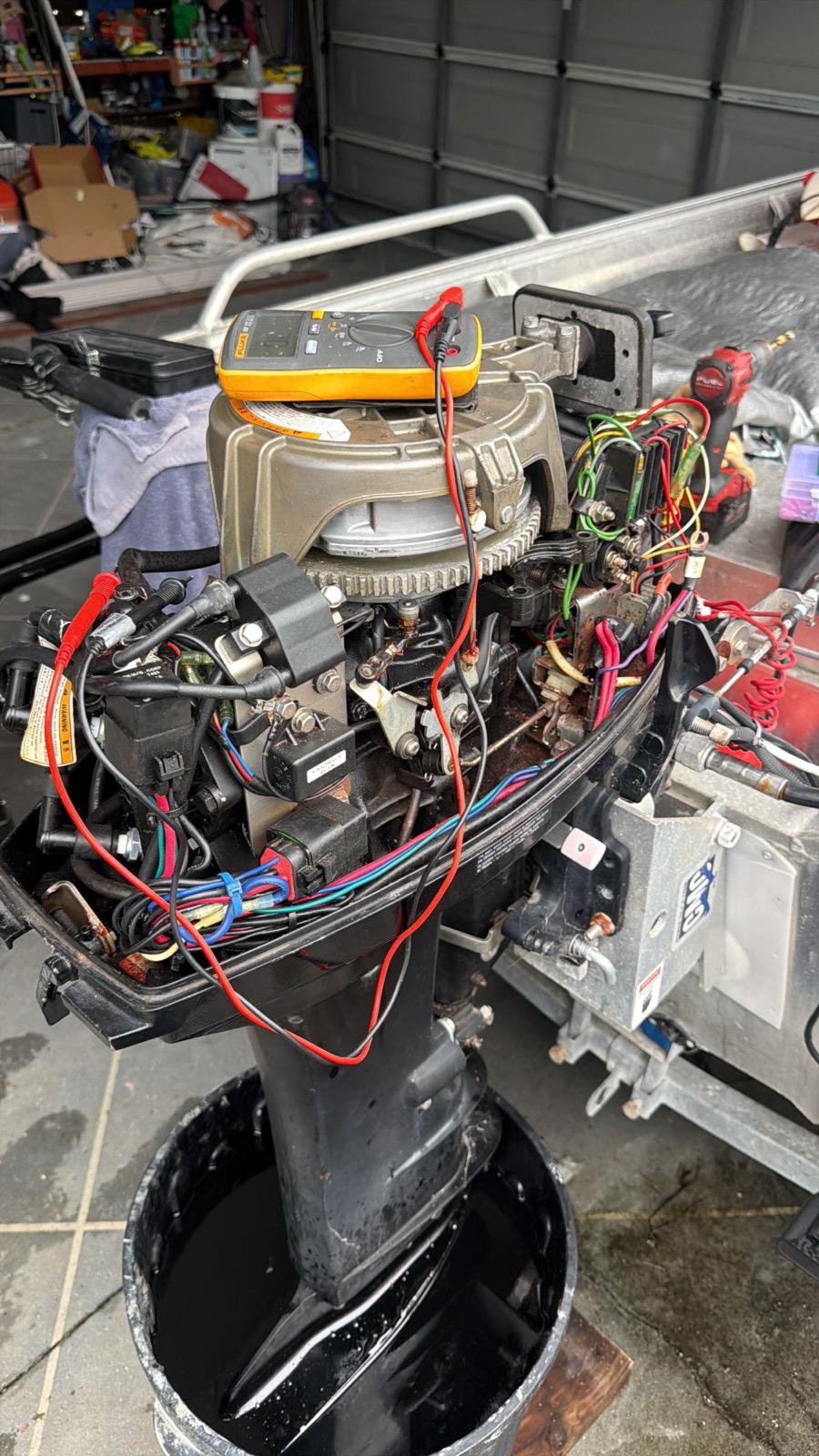 Multimeter on an outboard powerhead with the cowling off during no-crank testing